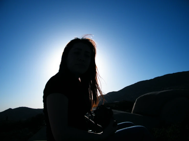 a girl sitting on the ground looking up to the sky