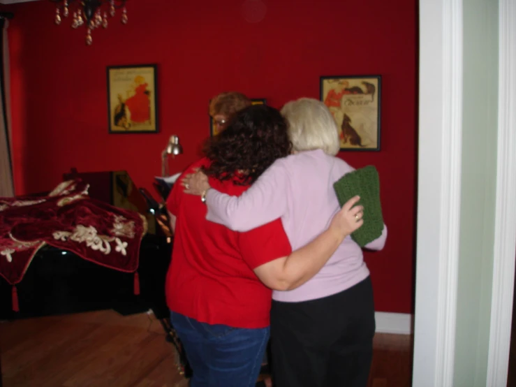 two women in front of the red wall hug