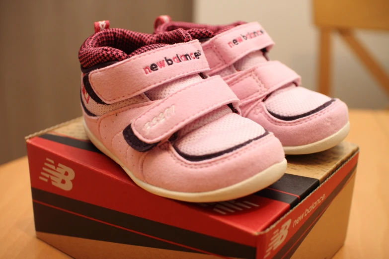 a pair of pink sneakers sitting on top of a shoe box