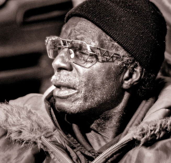 an older man wearing glasses and a cap is looking to the side