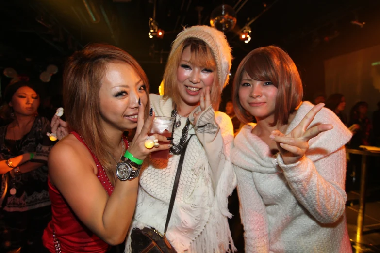 three beautiful young ladies with blonde hair holding a drink