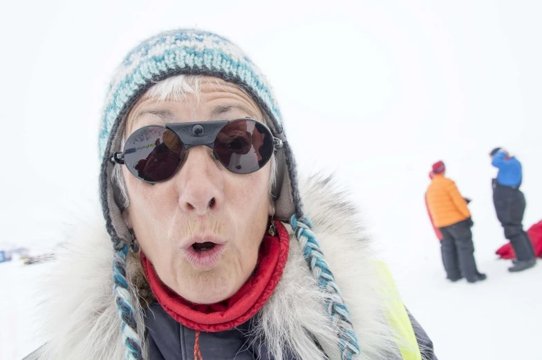 an old woman wearing sunglasses with others on a ski slope