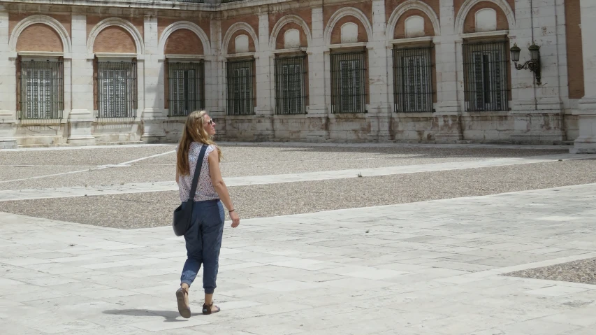 a woman walking through the courtyard next to a building