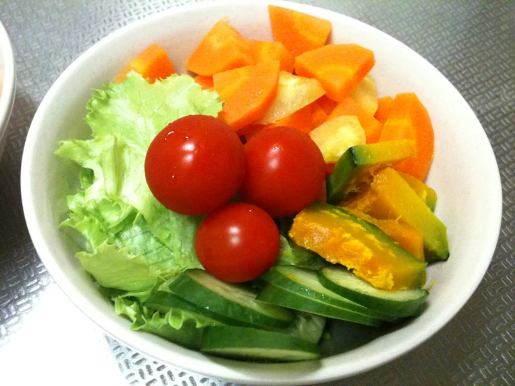 two bowls of salad and a salad with red tomatoes