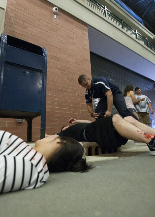 two people laying on the ground in front of a brick wall