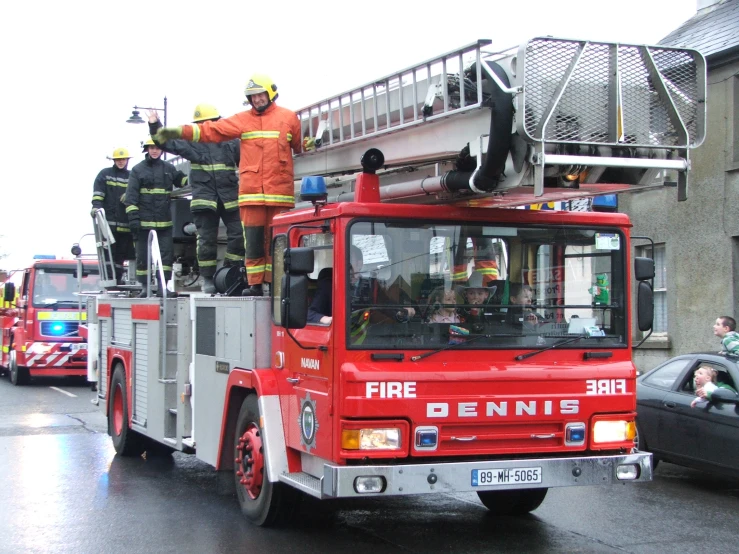 men in orange work on firetrucks near buildings