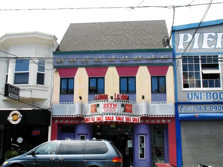 a small car parked in front of a movie theater