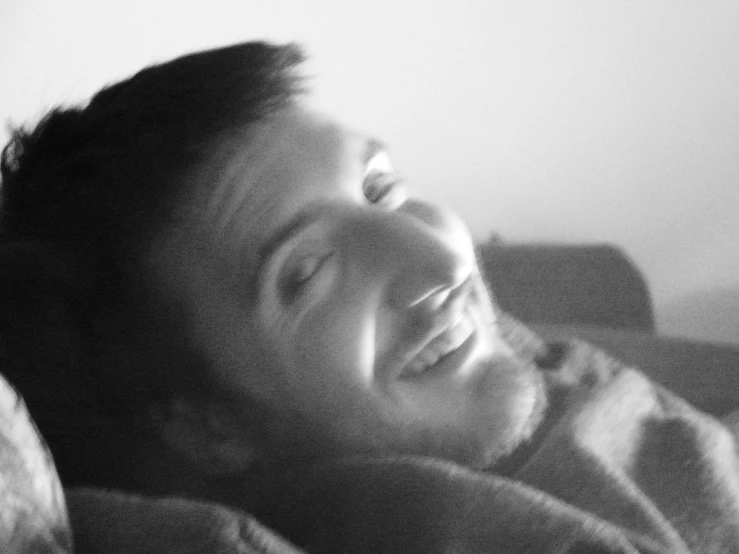 a man laying in bed smiling and laughing