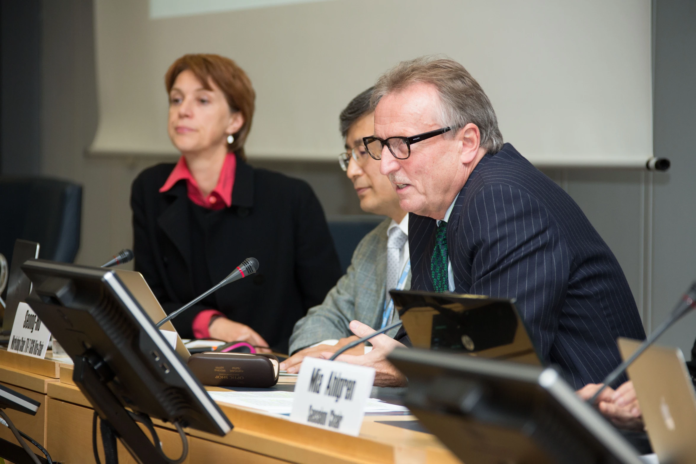 two people sitting at a desk with laptop computers