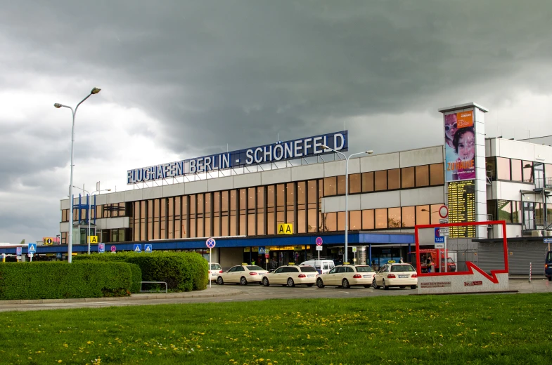 the building has large windows and has cars parked in front