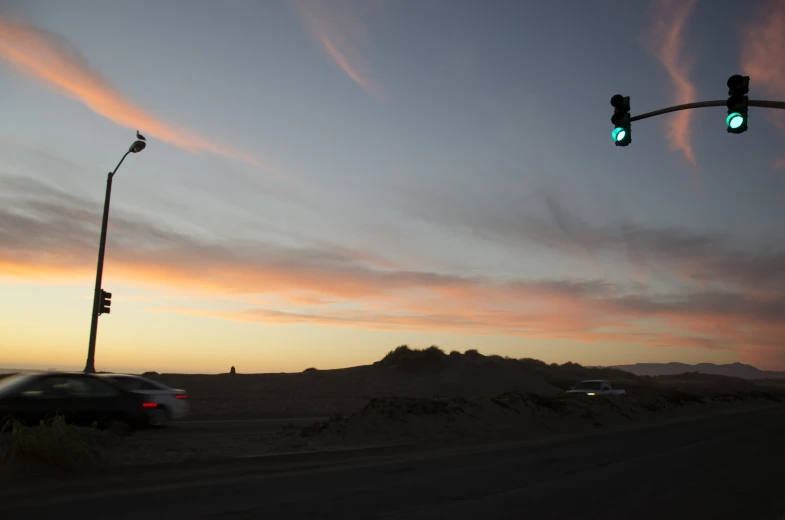 cars sit on the side of the road as the sun is setting