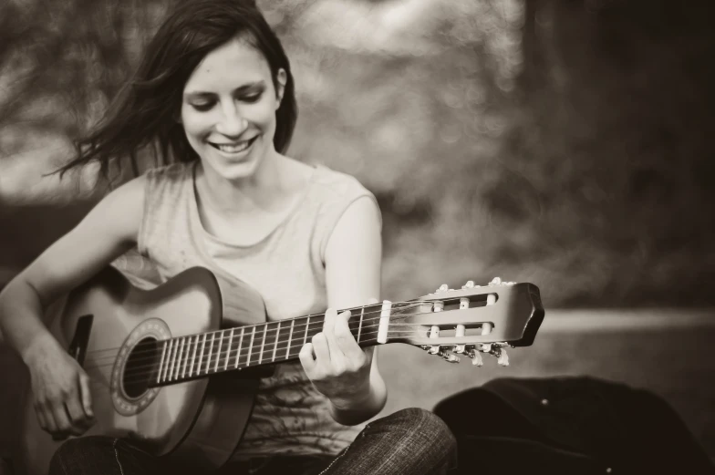 a girl sitting on the ground holding a guitar