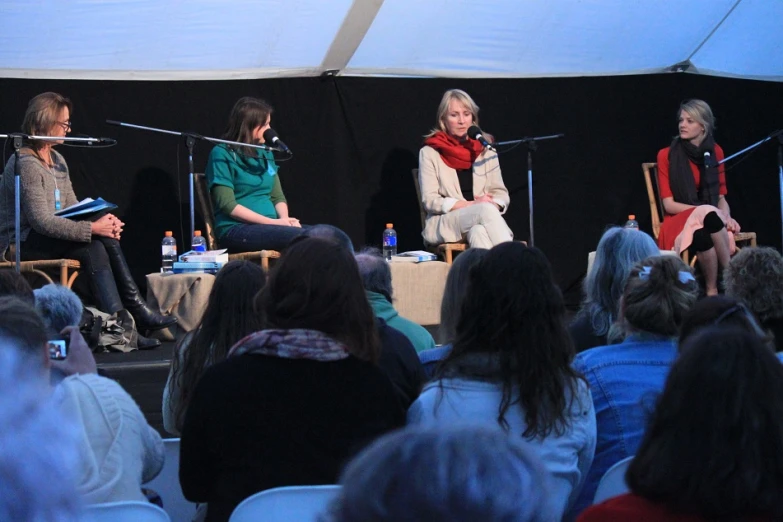 three people on stage speaking to an audience