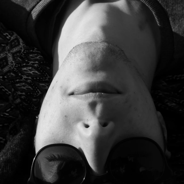 a person wearing glasses is laying on the ground