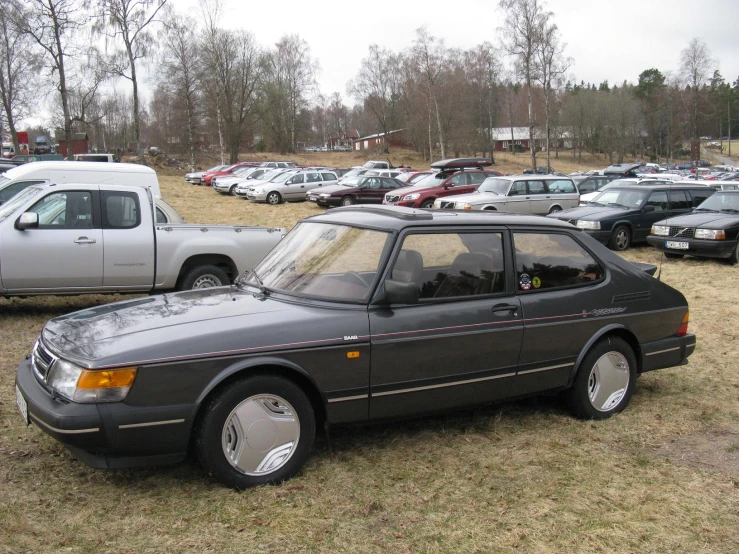 several cars are parked in a field with other cars behind them