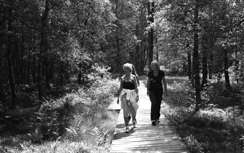 a couple of women walking along a wooden path