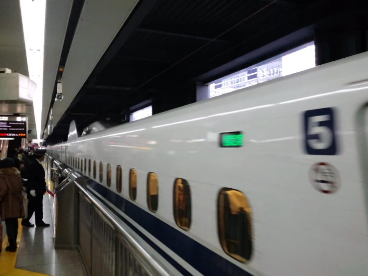 people walk by a train on a platform