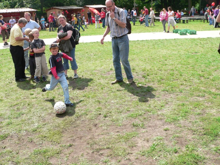 a man standing on a field with two small boys near a soccer ball