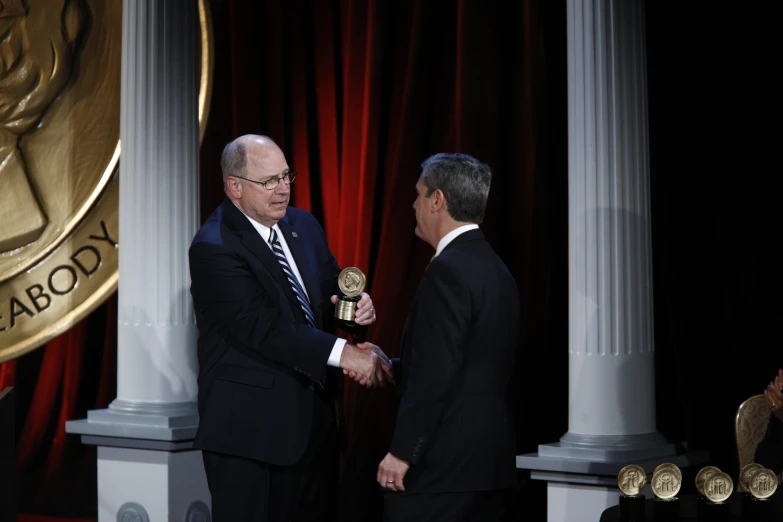 two men in suits shake hands at the same time