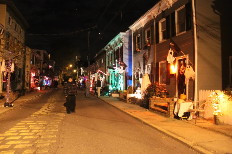 the people are walking in the street near a christmas light