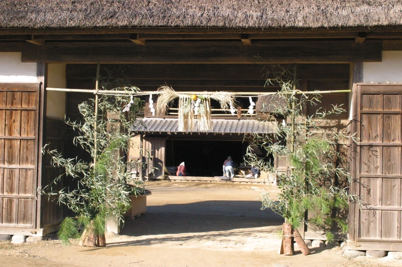 people are walking down the pathway under a bamboo house