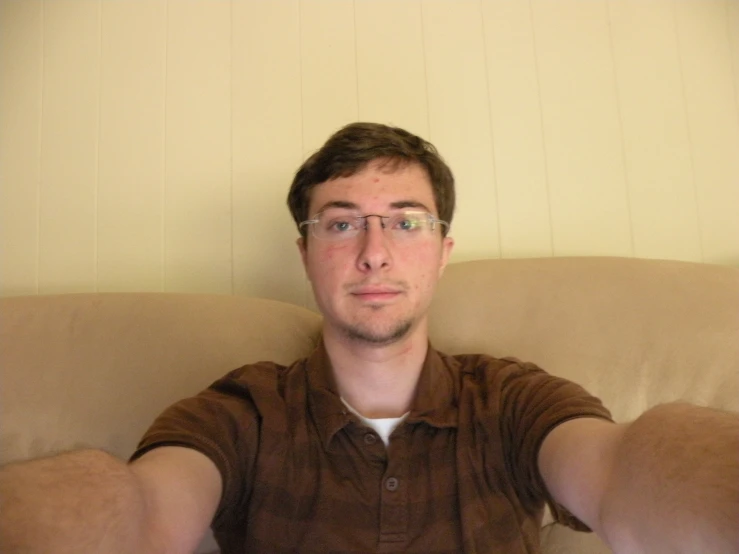 a man with glasses sits on a couch