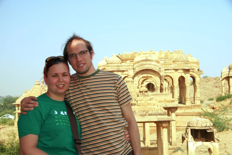 two people posing for a picture in front of an old building