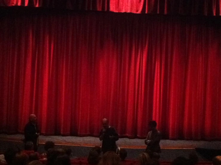 two people in front of a red curtain on stage