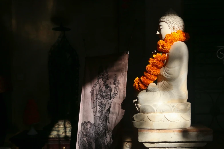 a statue holding orange flowers and an easel behind it