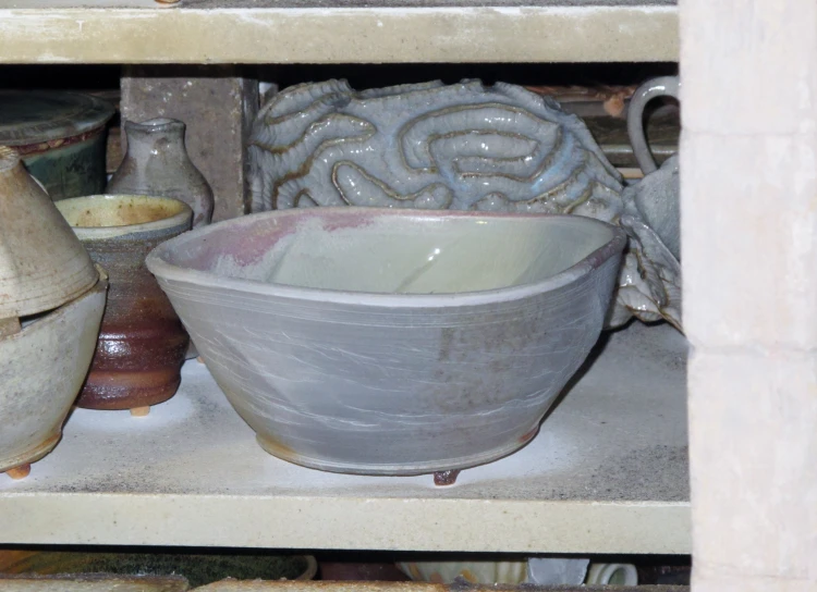 many vases and bowls are arranged on shelves