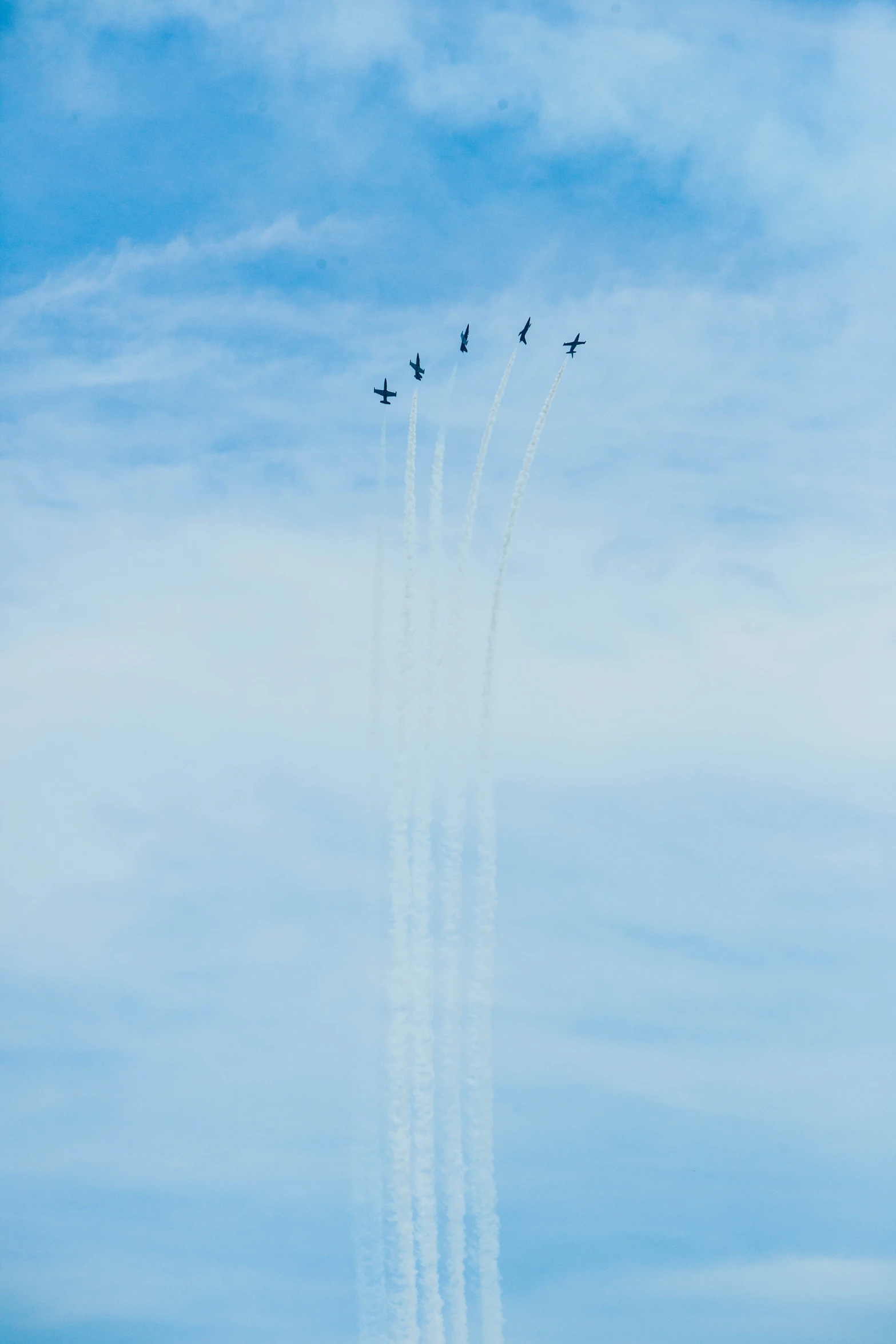 four airplanes flying in the air leaving trails