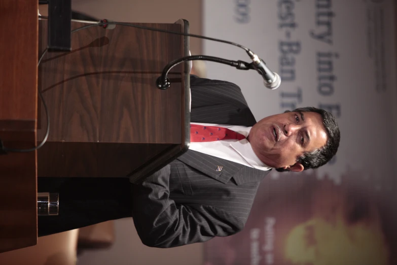 a man in a suit speaks at a podium