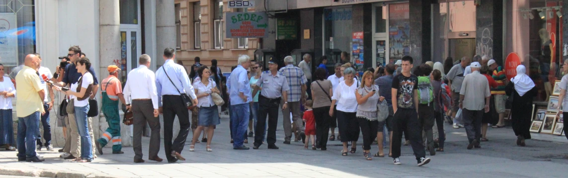 a large crowd of people stand near shops