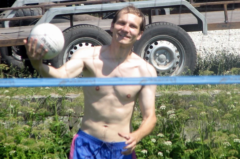 a man holding two soccer balls behind a fence