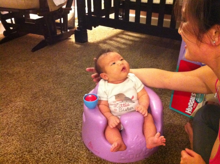 a woman is holding a baby in a purple chair