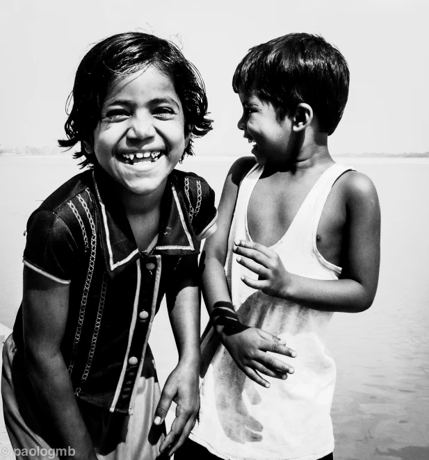 two young children stand next to the water