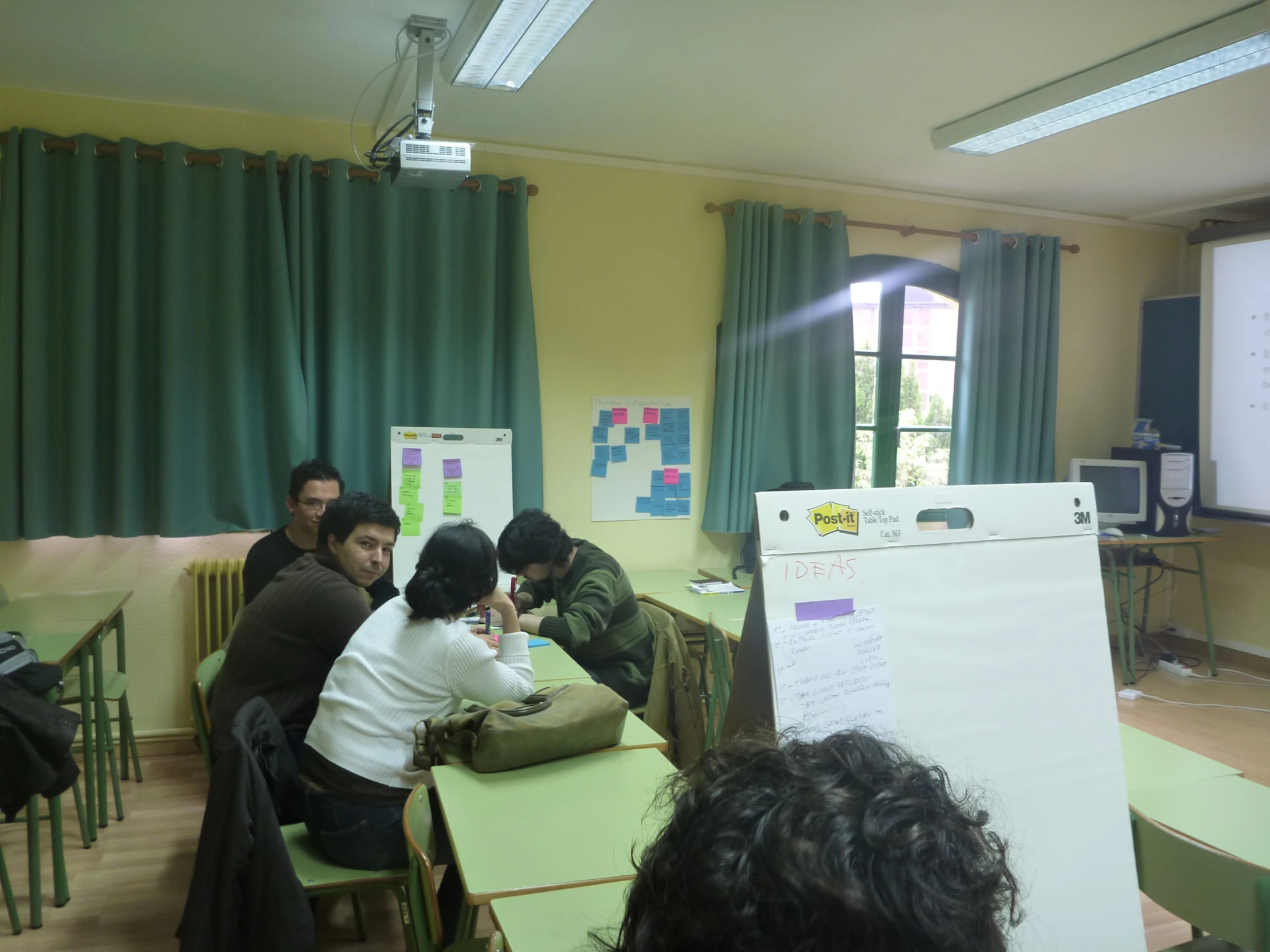 a group of people sitting around tables in a classroom