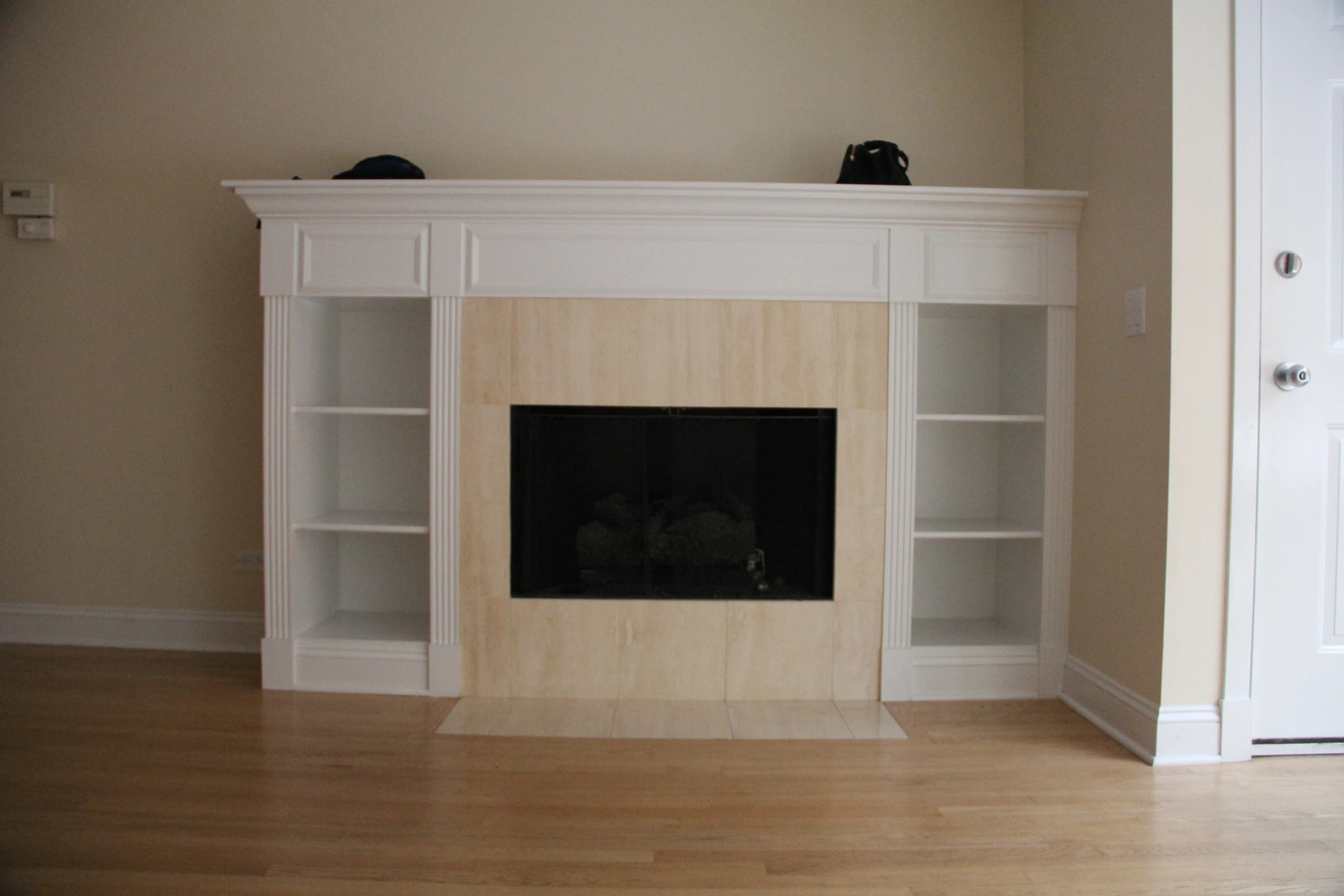 a empty room with white built in shelves and an open fire place