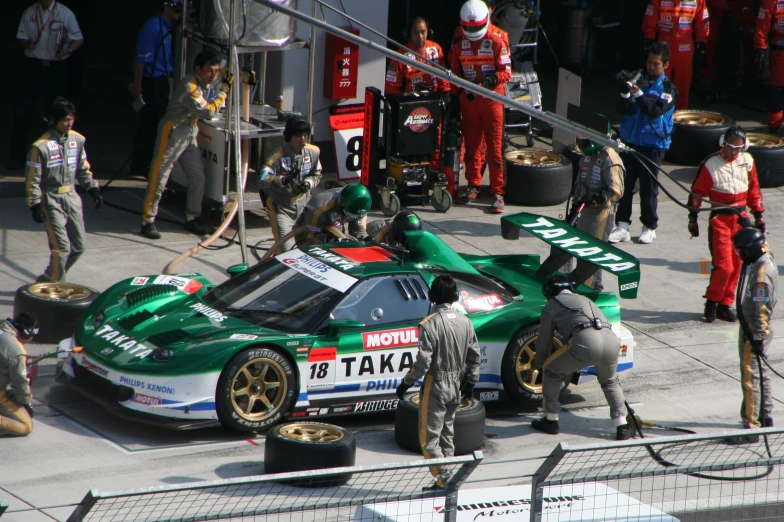 a racing car on a track surrounded by other workers