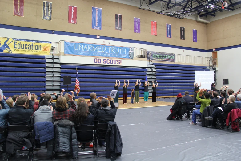 a group of people sit in chairs as a speaker stands in front of them