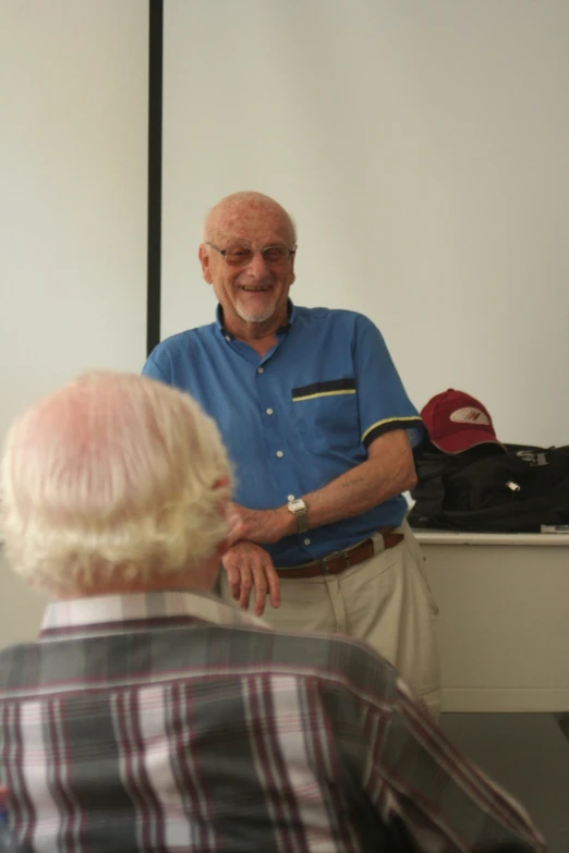 an older man wearing a blue shirt and tan pants