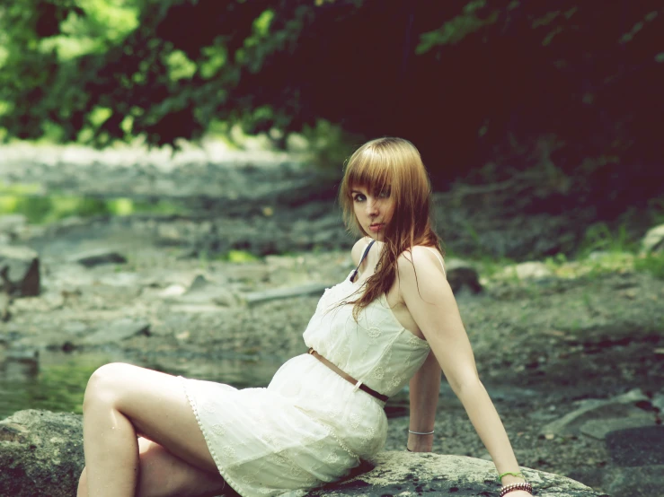 a young lady sitting on the ground near a water hole