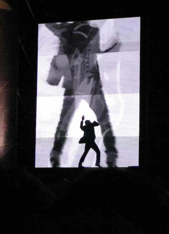 silhouetted man on stage holding a cell phone in his hand