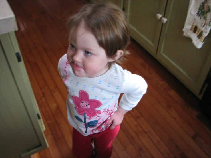 a child standing in the kitchen with a camera on her knee