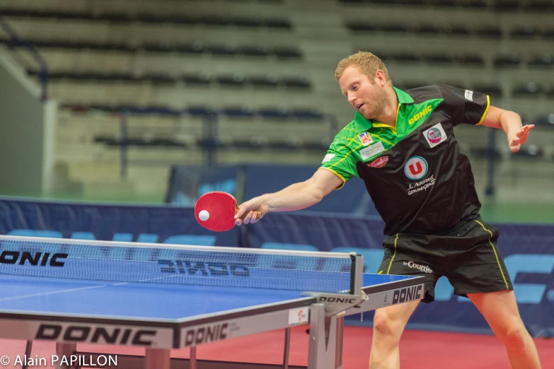 a man holding a ping pong paddle on top of a table