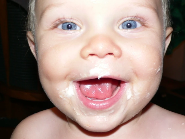 a baby making funny face with messy cream on it's head