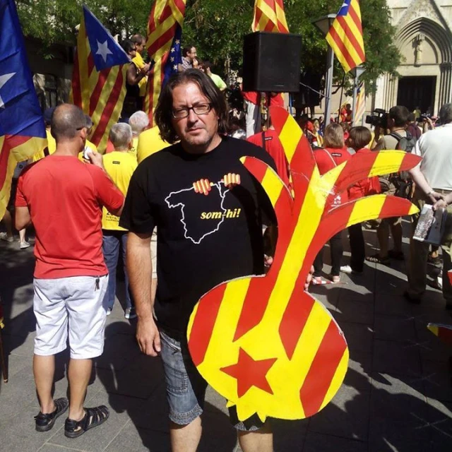 the man stands in front of a large group of people holding flags