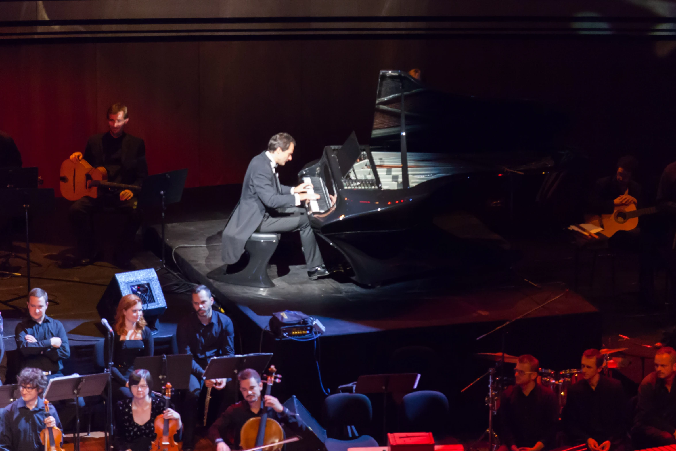 a piano is on stage next to a group of people