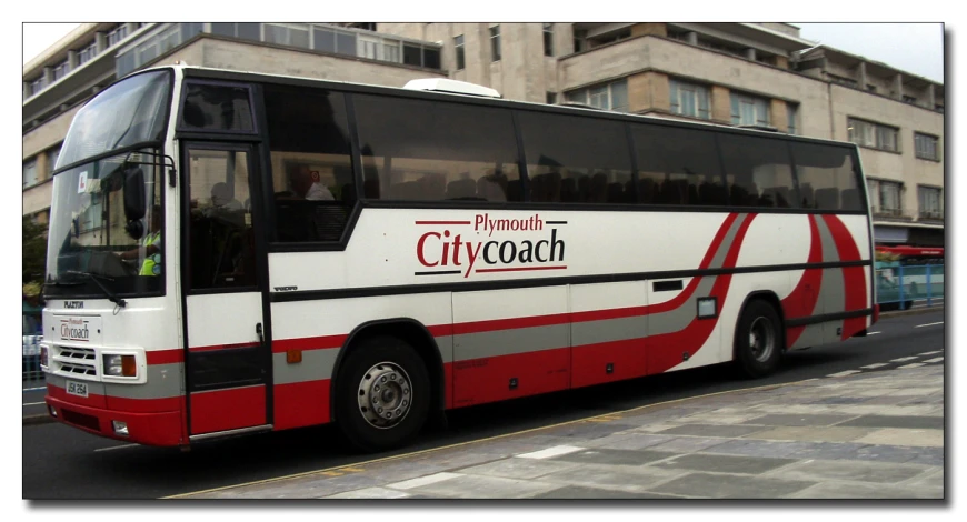 a red and white bus is parked on the side of the street