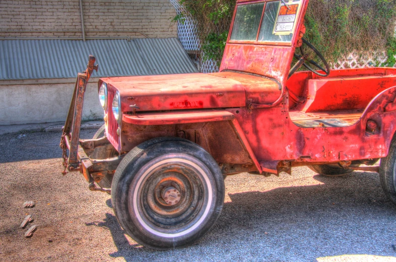 an old rusty red pick up truck parked on gravel